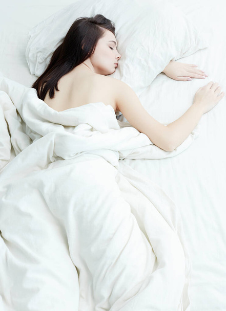 Retrato de estilo de vida de menina doce dormindo na cama. bela mulher sensual na cama branca da manhã - Foto, Imagem