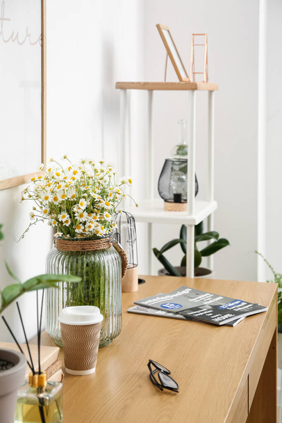 Moderno local de trabalho e vaso com camomila perto da parede de luz - Foto, Imagem