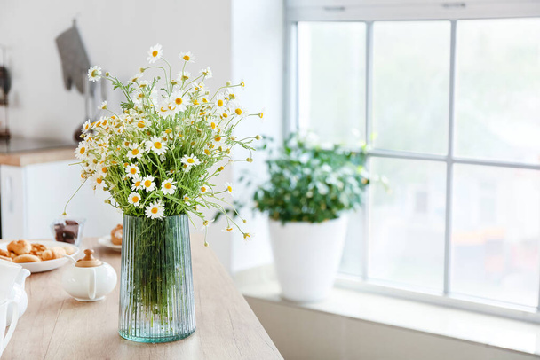 Vase with chamomiles on table in kitchen - Valokuva, kuva