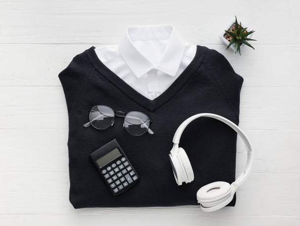 Şık okul üniforması, gözlük, kulaklık ve ahşap arka planda hesap makinesi. - Fotoğraf, Görsel