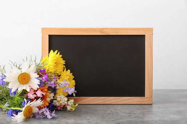 Blank chalkboard and bouquet of beautiful flowers on table - Photo, Image