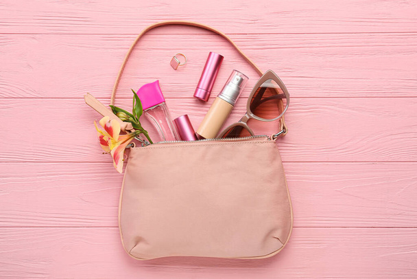 Elegante borsa con cosmetici decorativi e occhiali da sole su sfondo di legno a colori - Foto, immagini