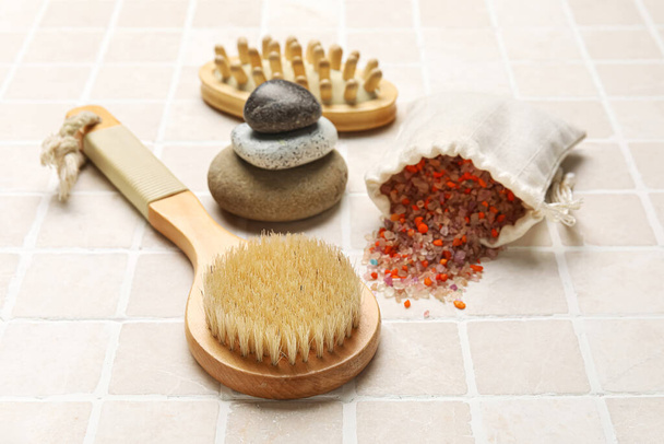 Different body brushes and sea salt on light tile background - Photo, Image