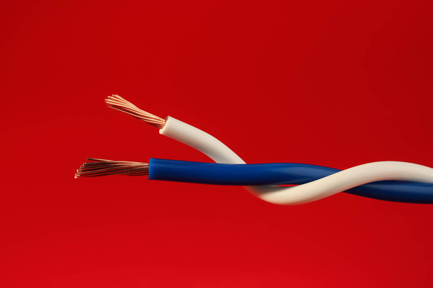 Two different electrical wires on red background, closeup - Photo, image