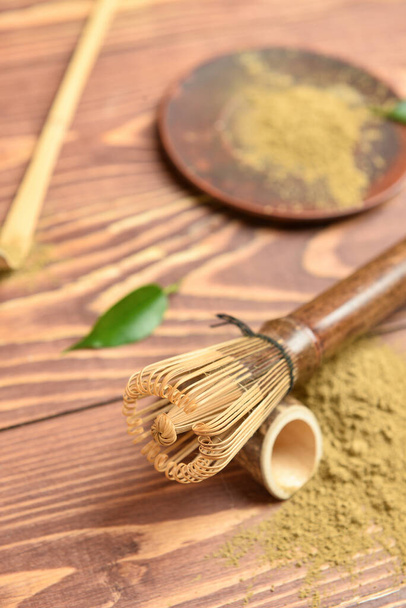 Powdered matcha tea and chasen on wooden background, closeup - Foto, Imagen