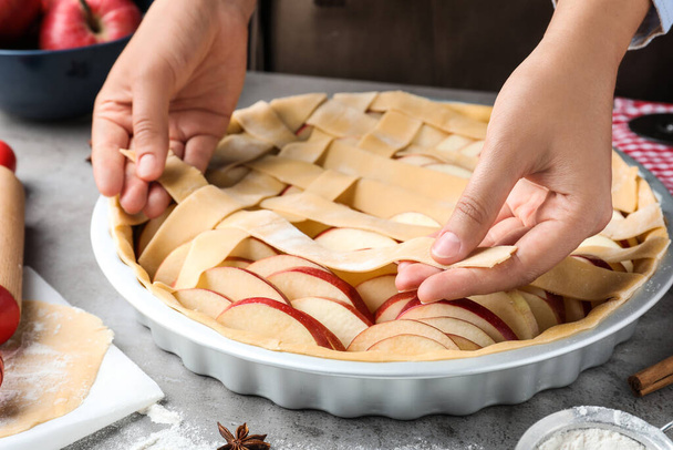 Woman decorating raw apple pie at grey table, closeup - Фото, зображення