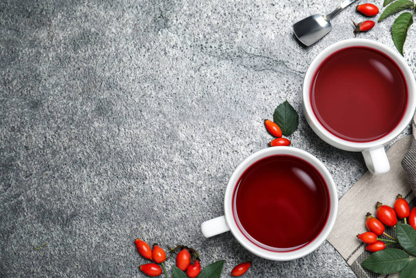 Fresh rose hip tea and berries on grey table, flat lay. Space for text - Photo, Image