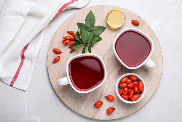 Fresh rose hip tea and berries on light table, flat lay - Photo, image
