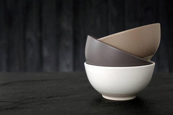Stylish empty ceramic bowls on black table, space for text. Cooking utensils - Foto, Imagem