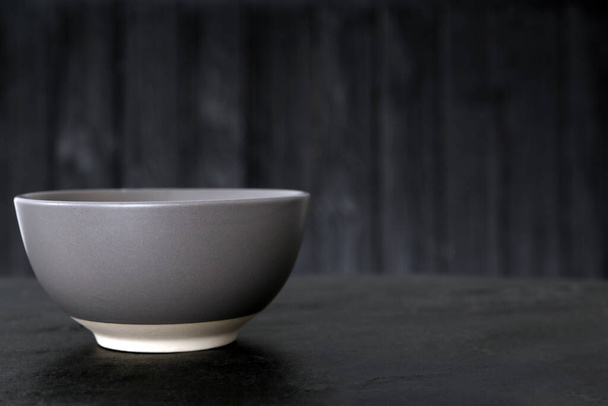 Stylish empty ceramic bowl on black table, space for text. Cooking utensil - Foto, afbeelding