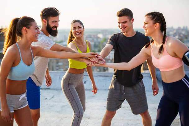 Group of happy fit people friends exercising together outdoor on rooftop. Sport, healthy life concept - Photo, image