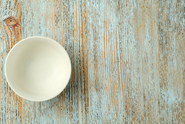 Stylish empty ceramic bowl on light blue wooden table, top view and space for text. Cooking utensil - Fotó, kép