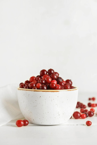 Bowl with healthy cranberry on light wooden background - Foto, imagen