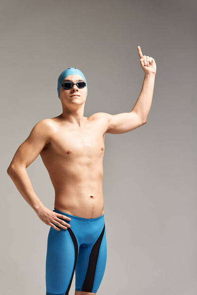 Young professional swimmer man indicates with fingers up showing a blank space. - Valokuva, kuva