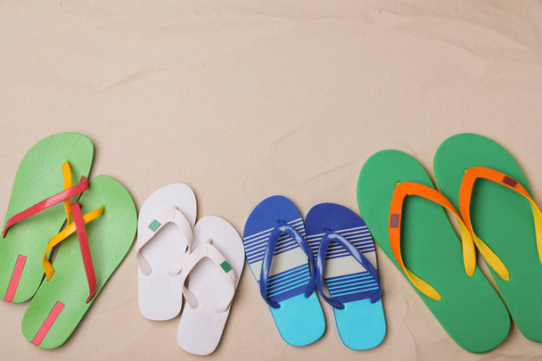 Different bright flip flops on sand, flat lay. Space for text - Фото, изображение