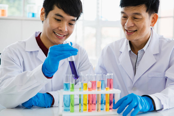 2 scienziato asiatica uomini adulti tenere e guardare la provetta come liquido e sorridente sguardo sentire felice e casual che questo test risultato in laboratorio. - Foto, immagini