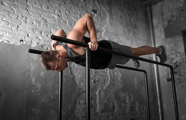 man doing push-ups on parallel bars in gym - Photo, image