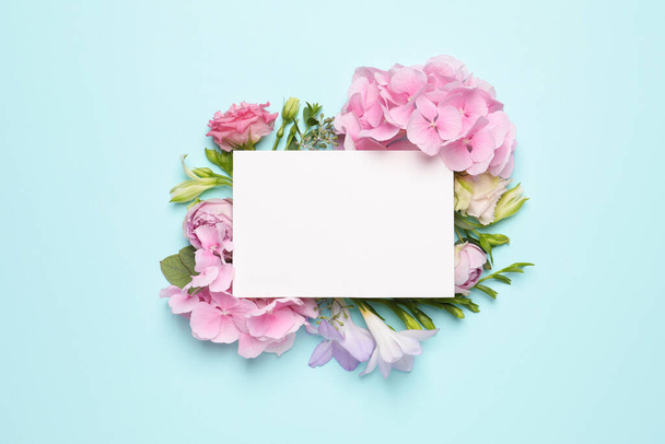 Beautiful composition with hortensia flowers and blank card on light blue background, top view. Space for text - Фото, зображення
