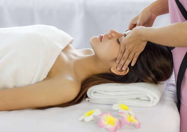 Adult beautiful asian women black long hair sleep for head massage spa service with covered wrap by white towel on her look feel relax and blurry with flowers background. - Photo, Image