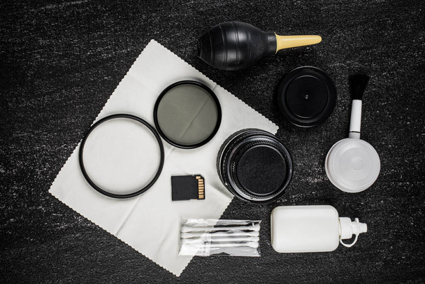 vista dall'alto dello spazio di lavoro fotografo con kit di pulizia, scheda di memoria e USB su sfondo tavolo nero - Foto, immagini