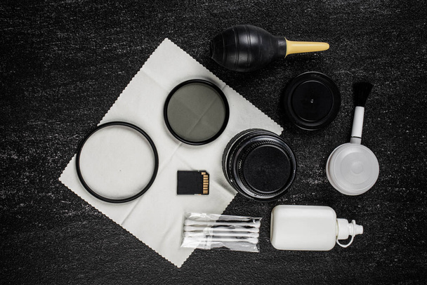 vista dall'alto dello spazio di lavoro fotografo con kit di pulizia, scheda di memoria e USB su sfondo tavolo nero - Foto, immagini