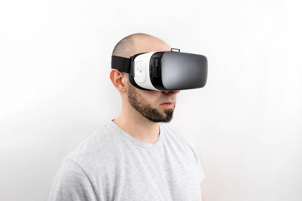 Retrato de um homem caucasiano em óculos VR sobre um fundo branco. O conceito de realidade virtual e entretenimento moderno. - Foto, Imagem