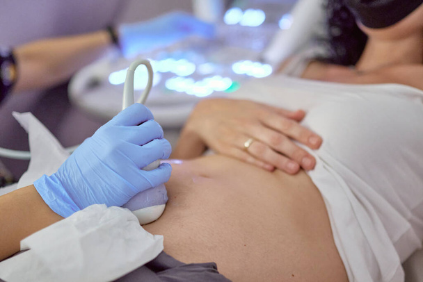 manos de una doctora realizando un ultrasonido a una mujer embarazada en un hospital. concepto de gestación y atención médica en el embarazo - Foto, imagen