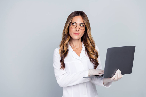 Portrait of attractive minded wavy-haired woman doc using laptop copy space analysis isolated over grey pastel color background - Foto, afbeelding