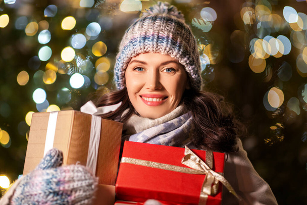 happy woman with christmas gifts over lights - Фото, зображення