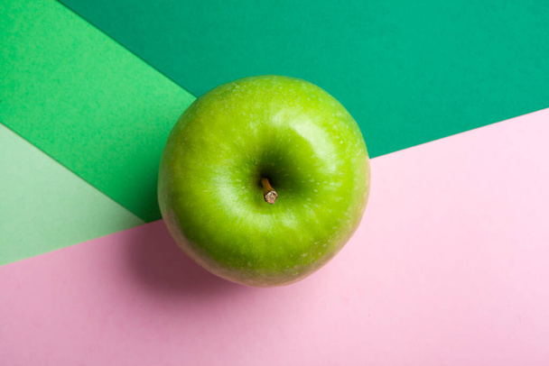Top view whole green granny smith apple isolated on green and pink geometric background - Zdjęcie, obraz