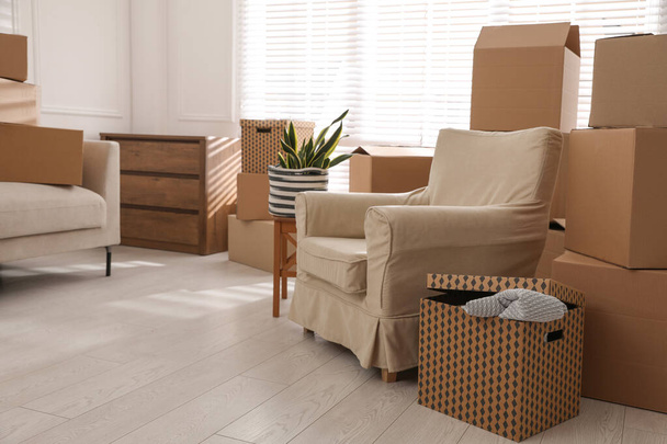 Furniture and cardboard boxes with packed stuff in room. Moving day - Fotoğraf, Görsel