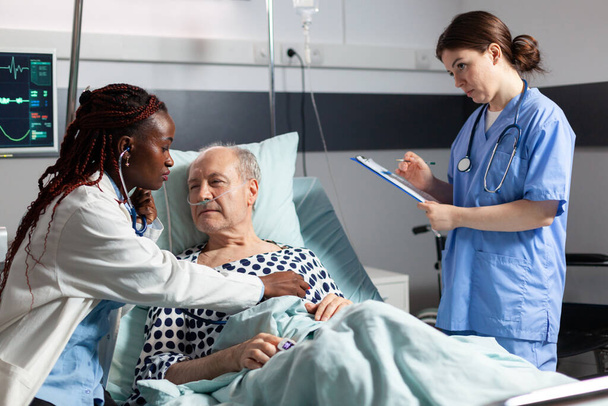 Cardiologue afro-américain vérifiant l'examen du cœur du patient âgé - Photo, image