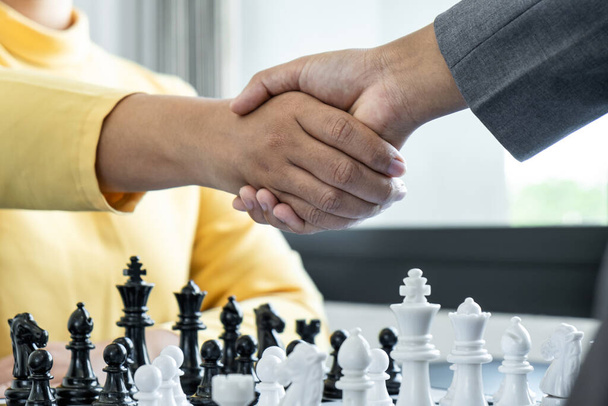 Επιχειρηματίας χειραψία μετά το παιχνίδι σκάκι και τη σκέψη για συντριβή στρατηγικής ανατρέψει την αντίθετη ομάδα και την ανάλυση ανάπτυξης για τη νίκη και την επιτυχία. - Φωτογραφία, εικόνα