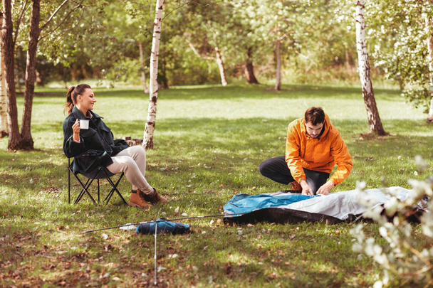 happy couple setting up tent outdoors - Valokuva, kuva