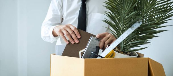 Geschäftsmann Mitarbeiter packt Notizbuch und nimmt persönliche Gegenstände in braunen Karton, um Arbeitsplatz zu verlassen, wenn Kündigung oder Arbeitsplatzwechsel - Foto, Bild