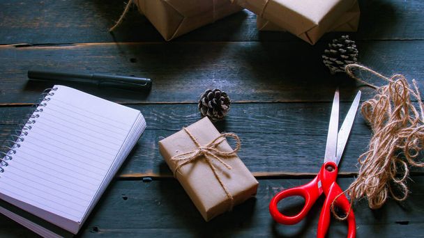gift wrapping from Kraft paper wrapped with twine, the concept of handmade, placed on black wooden table - 写真・画像