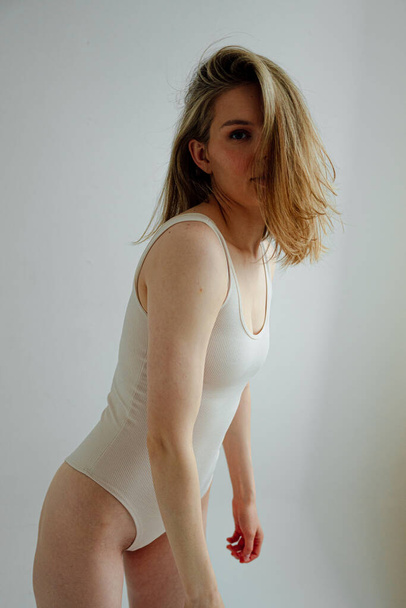 menina bonita com corpo atlético vestindo bodysuit esportivo posando em estúdio de luz  - Foto, Imagem