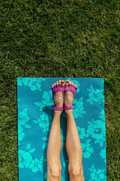 Yoga in the morning. Young woman practicing on yoga mat on green lawn - Valokuva, kuva