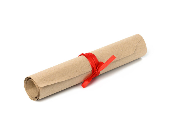 завернутый в рулон коричневой крафтовой бумаги и перевязанный красной лентой - Фото, изображение