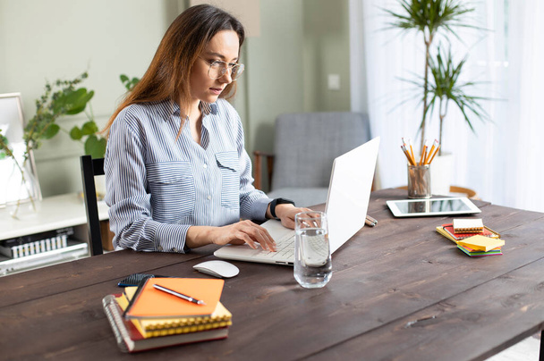 Una joven que trabaja con un portátil. Freelancer femenina conectándose a internet en casa. Blogger escribiendo nuevo artículo. - Foto, imagen