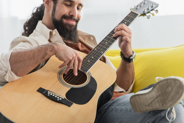 desfocado hispânico homem tocando guitarra acústica em casa - Foto, Imagem