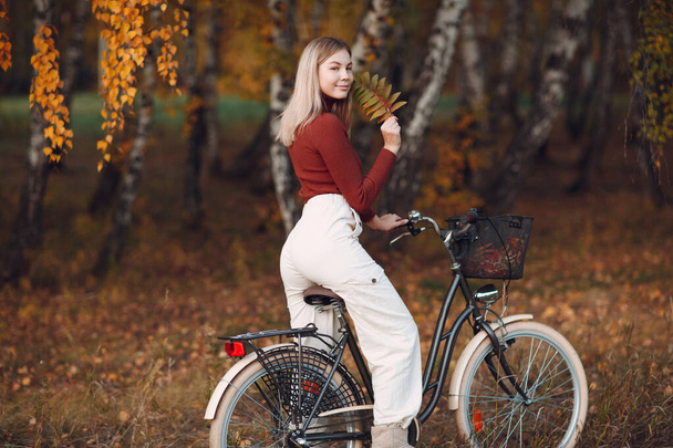 Ευτυχισμένη δραστήρια νεαρή γυναίκα ιππασία ποδήλατο στο πάρκο φθινόπωρο - Φωτογραφία, εικόνα