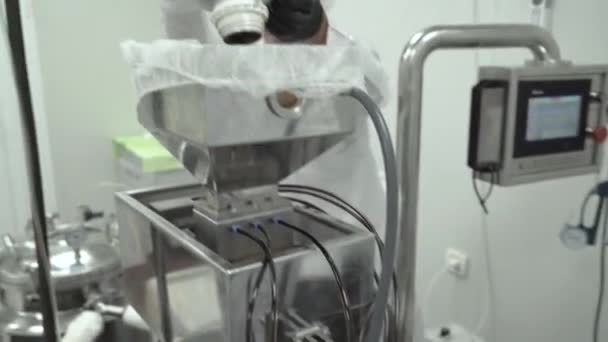 Científico con guantes negros trabajando en una máquina compleja y vertiendo aceite de cáñamo en ella - Imágenes, Vídeo