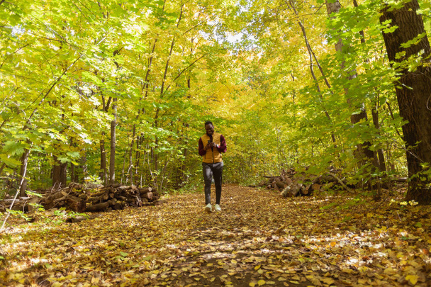 African american student walking in the park in autumn season - Foto, imagen