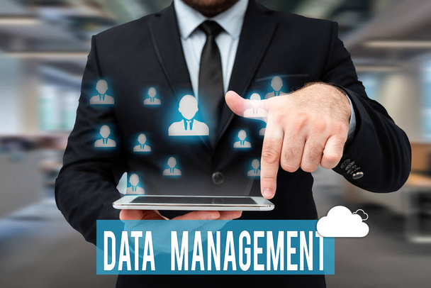 Writing displaying text Data Management. Business idea disciplines related to managing data as a valuable resource Man In Uniform Standing Holding Tablet Typing Futuristic Technologies. - Photo, Image