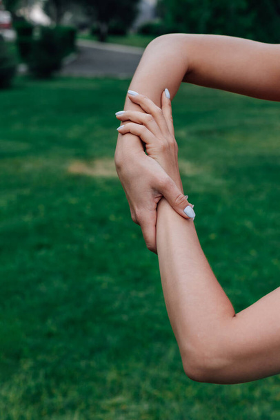close-up of two female hands holding each other on green grass in park, concept of care and support - Φωτογραφία, εικόνα