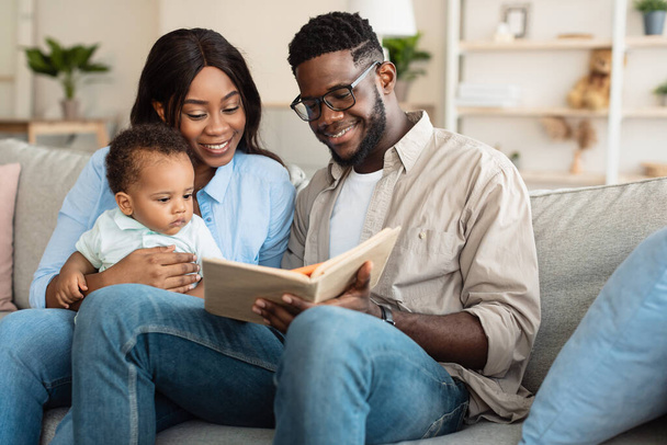 Portrait of happy black family reading book for infant - Photo, Image