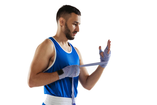 Side view cropped portrait of professional boxer tying boxing handwraps isolated over white background. Training - Photo, image