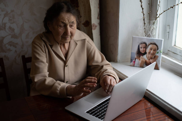 mujer muy vieja usando el ordenador portátil sentado en casa - Foto, Imagen