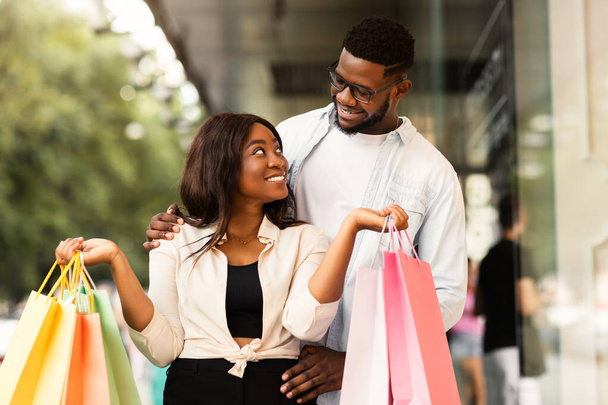 Beautiful black couple holding shopping bags looking at each other - Photo, Image